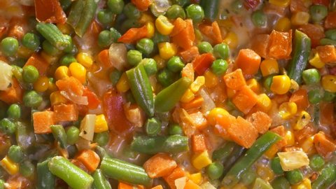 Vegetable stew. A dish of frozen vegetables is cooked in a frying pan. Asparagus, corn, pepper, peas.