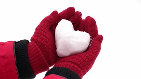 Close-up view slow motion video of small white snow heart in hands of woman. Female hands in warm red gloves holding cute snowy heart. Love to winter season, St. Valentine's Day, Christmas concept