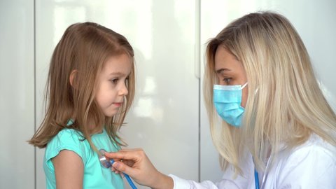 Female doctor pediatrician uses stethoscope listen heart of child girl patient. Lung breathing check. Medicine and healthcare concept.