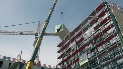Berlin, Germany, 06.01.2021, Crane lifting a wooden building module to its position in the structure. Construction site of an office building in Berlin. The new structure will be built in modular timb
