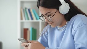 Happy teenage girl school pupil wearing headphones distance learning online at virtual lesson class with teacher typing browsing chatting send sms, studying at home. make pandiculation. 4k