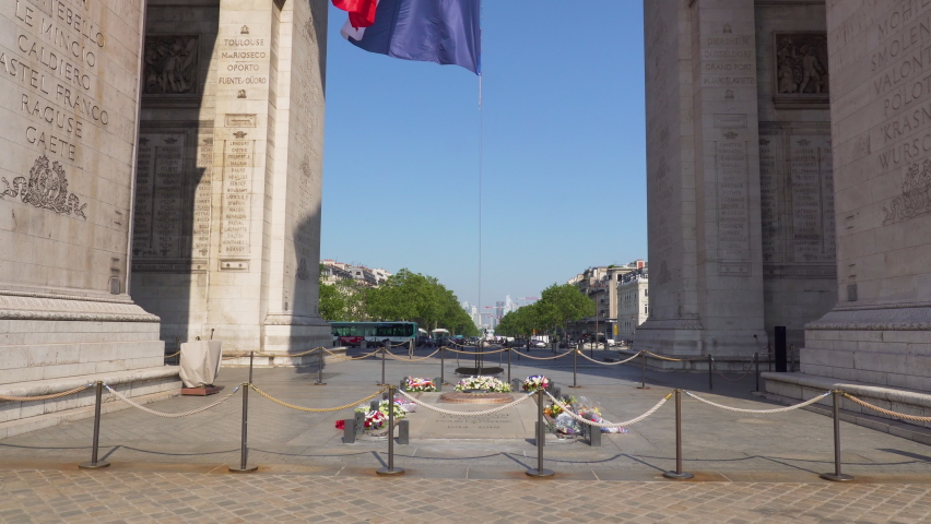 Tilt over the Tomb of the Unknown Soldier and the French Flag waving under the Arc de Triomphe - Paris, France