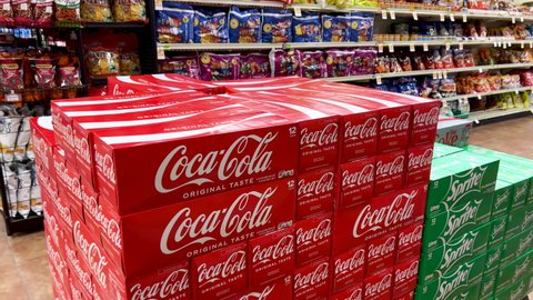 Sacramento, CA, USA January 28th, 2022 Shopper graving a box of cans of Coca Cola brand soda drink in a supermarket aisle