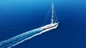 Aerial drone video of beautiful wooden deck classic sailing yacht cruising in open ocean deep blue sea