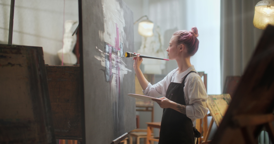 Portrait of Talented Woman Artist Working on Abstract Painting, Uses Paint Brush To Create Abstract Picture. Dark Creative Studio Large Canvas Stands on Easel. Royalty-Free Stock Footage #1086158801