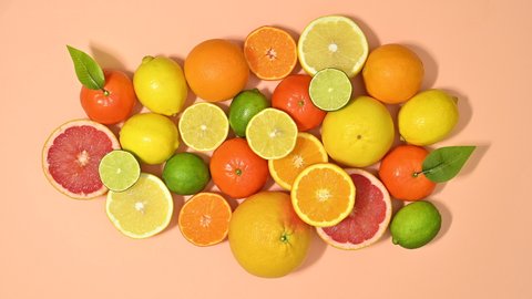 6k Fresh ripe citrus fruits filling pastel orange background. Stop motion flat lay