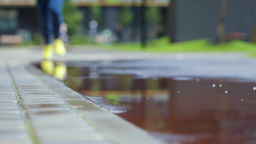 Female sports woman jogging outdoors, stepping into puddle. Single runner running in rain, making splash. Slow motion