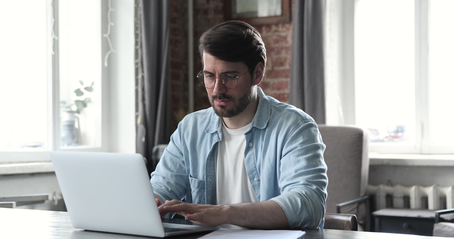 Annoyed millennial man in glasses manage financial documents at home office read reports feel angry upset surprised with bad news failing sales. Distressed young businessman receive tax penalty paper Royalty-Free Stock Footage #1086169430