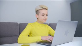 Young woman studying online. White female with short dyed hair typing on laptop computer. Tom boy person using modern notebook pc for distant work during lockdown. 4k stock video of freelancer at work