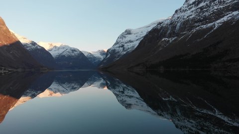 Sunset colors and reflections of the lake Lovatnet which is surrounded by snowy mountains