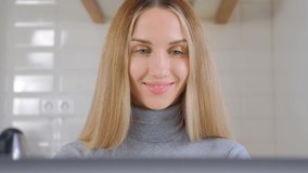 Beautiful woman working on computer. Video portrait of pretty blonde female doing distant freelance work online during lockdown. Freelancer person using laptop with cheerful smile in 4k stock video