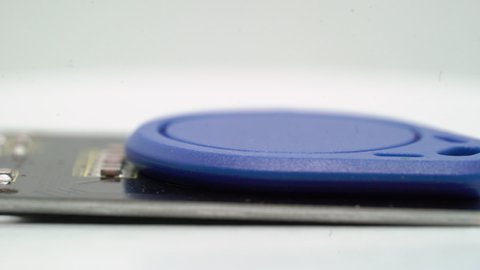 RFID key keychain blue electronic component. Electronic proximity key for intercom. Access for staff. Rotate at white isolated. Copy clone digital card for entrance lock. Security.