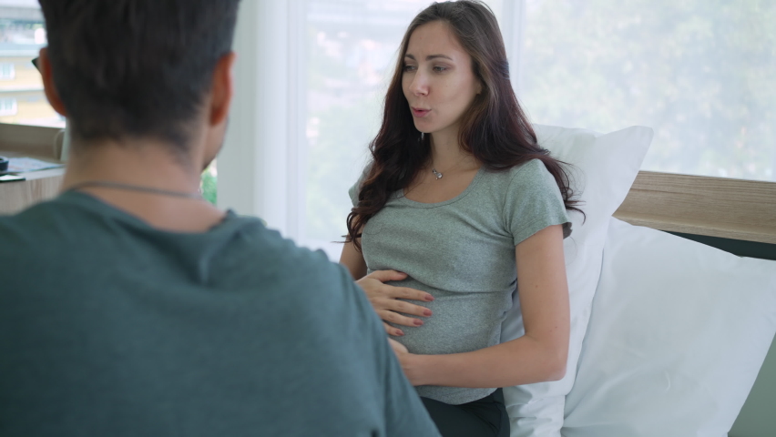 Caucasian Pregnant Couple Talking Together in Bedroom