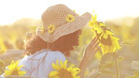 Portrait of beautiful young carefree asian woman posing in field with sunflowers, enjoying nature. Woman smells flowers against background of nature and field of sunflowers. 