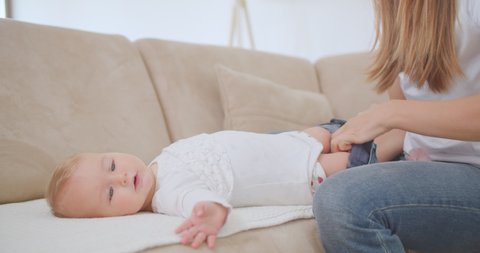 Young mother dressing her baby while it has hiccups in the living room