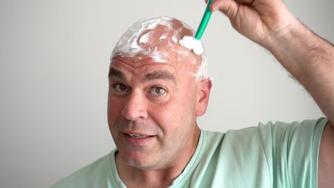 Close up of Caucasian man shaving his head with a razor