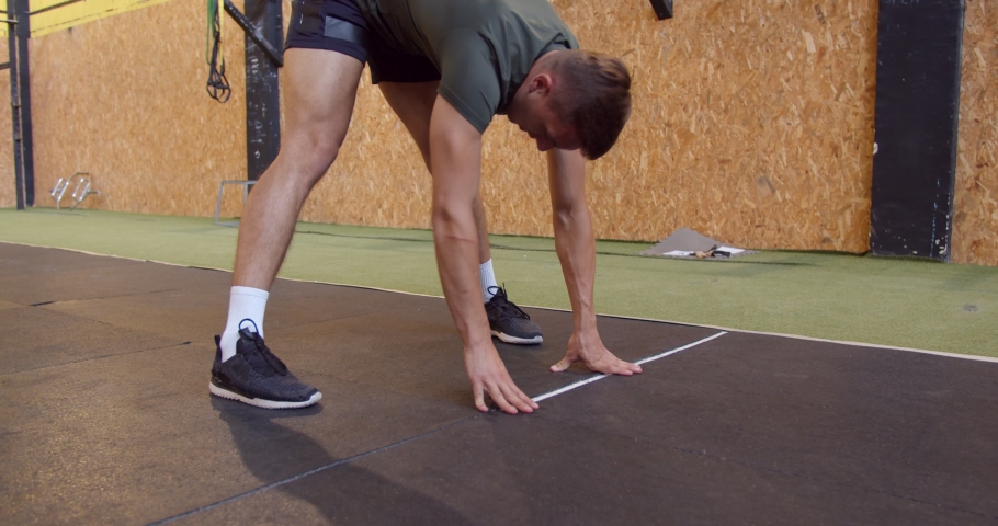 Handsome and fit male is stretching and warming up his body before training