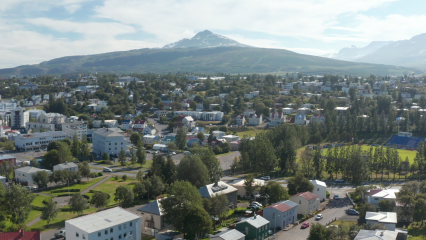 Beautiful scenery of snow capped mountain peak above town. Fly above houses along streets.