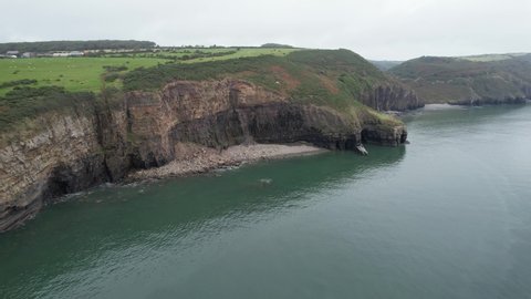 Beautiful preserved nature at sea coast. Aerial panoramic view of tall rocky cliffs steeply falling to water. Amroth, South Wales, UK