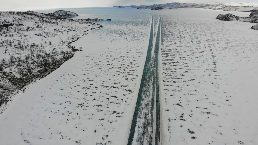  Ice road to Olkhon Island from the air. Frozen Lake Baikal, covered with snow. Winter travel by car.
