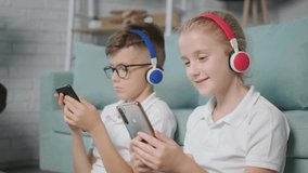 Portrait of twins girl and boy listening to music using phone and headphones, having fun at home. - Powered by Shutterstock - Get 15% off with code: PIKWIZARD15