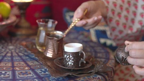 Pouring turkish coffee from cezve into cup, slow motion.