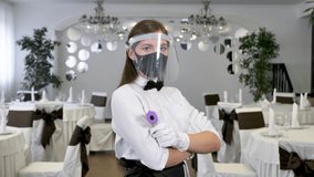 Waitress is a woman wearing a face mask and holding an infrared thermometer on her forehead to check the body temperature for symptoms of the virus in customers. - Powered by Shutterstock - Get 15% off with code: PIKWIZARD15