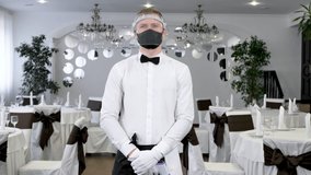 A male waitress wearing a face mask and with an infrared thermometer for her forehead to check her body temperature for symptoms of the virus. - Powered by Shutterstock - Get 15% off with code: PIKWIZARD15