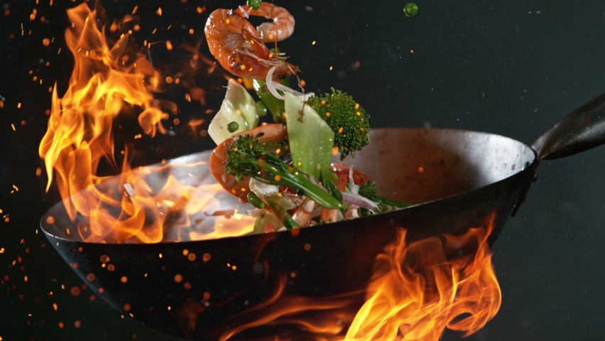 Super Slow Motion Shot of Wok Pan with Flying Ingredients in the Air and Fire Flames. Filmed on High Speed Cinema Camera at 1000 FPS. Royalty-Free Stock Footage #1086192224