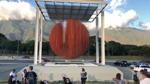 Caracas, Venezuela January 15, 2022: People enjoying The Sphere of Caracas, popularly known as the Soto Sphere urban art work by master of Kineticism Jesus Soto, with the Francisco Fajardo Highway and