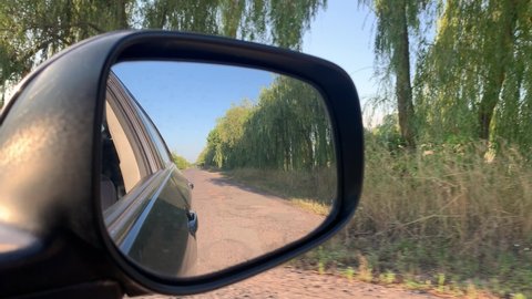 Rear view mirror, The car is moving on a country road. Rear view mirror, The car is moving on a country road. Reflection of nature in the rearview mirror of a car.