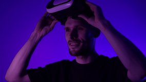 Man using VR virtual reality glasses. Futuristic metaverse universe games and future in digital technology. Entreatment and NFT in neon colorful space. Happy male. Slow motion soft focus video