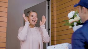 Courier delivering flowers and gift box to woman at her home. Happy and excited mature woman receiving bouquet of flowers for birthday, smiling and thanking delivery man. Delivery, celebration concept - Powered by Shutterstock - Get 15% off with code: PIKWIZARD15