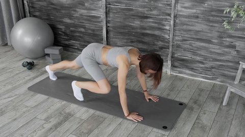 Brunette woman making exercises for abs and core muscles. Sporty woman training abdominal muscles on mat. Fitness woman working out for better health indoors. Bodycare and fitness concept. 4K, UHD