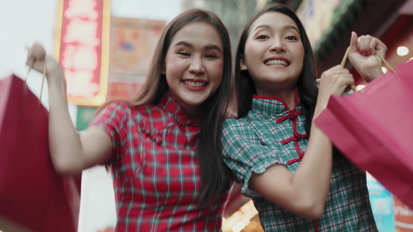 Asian woman in cheongsam dress with shopping bag. happy smiling woman holding colorful shopping bag in  china town.People traveling in city lifestyle at outdoor at China town street food market. 