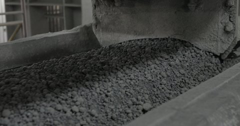 A lot of gray pebbles on the transporter in factory. Location not relevant. A lot of rocks on conveyor. A lot of stones on conveyer. 