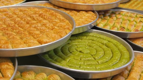 Traditional Turkish dessert Baklava close-up in the local Baklava shop in Gaziantep, Turkey. Trays of delicious baklava display in showcase of baklavalari cafe. Slow zooming out