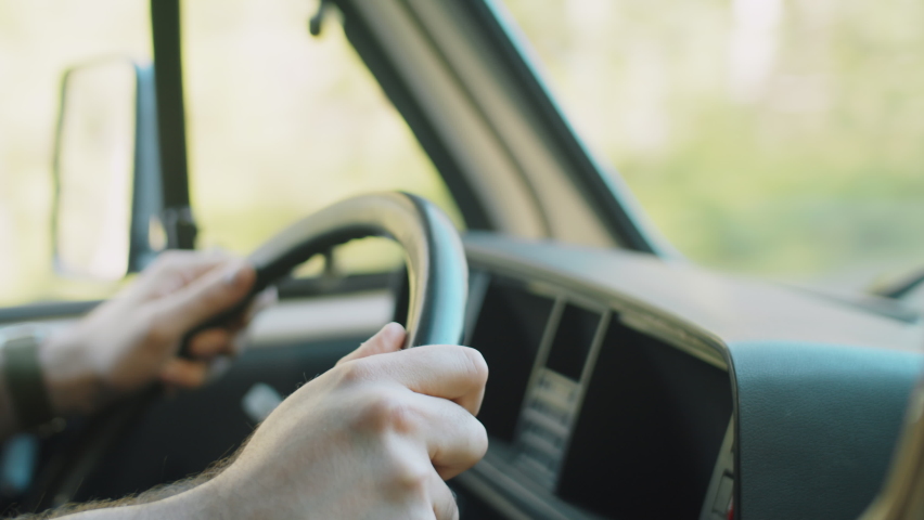Close up view of cheerful bearded man in beanie hat driving car and smiling