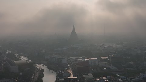 flying above Phra Prathom Chedi city with mist slowly form town over the clouds 4k stock footage