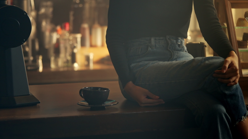 Asian woman sitting on bar counter enjoy drinking black coffee at coffee shop in the morning. Confidence female holding coffee cup drinking scented hot coffee. Small business cafe restaurant concept. | Shutterstock HD Video #1086213332