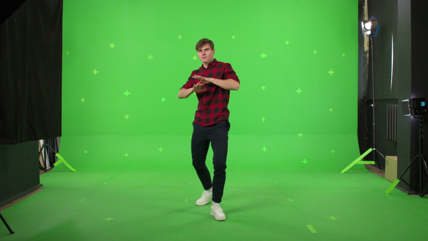 A young man dancing on a green screen background. Attractive guy makes a gesture with her hands as if swipping the page to the side . Chroma key Royalty-Free Stock Footage #1086216401