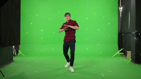A young man dancing on a green screen background. Attractive guy makes a gesture with her hands as if swipping the page to the side . Chroma key