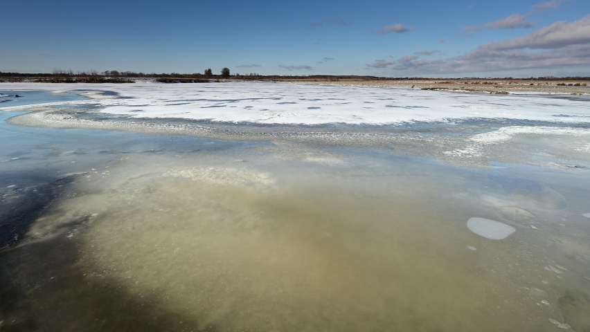 Completely frozen overflow of the Bug river in winter, coastal meadows, snow, ice, sunny day, sunrise