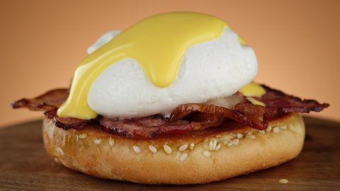 Egg Benedict. Pouring French Hollandaise sauce on poached egg. Traditional American breakfast. 4K UHD video