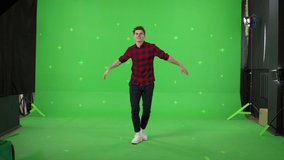 A young man dancing on a green screen background. Attractive guy making heart sign with fingers . Chroma key