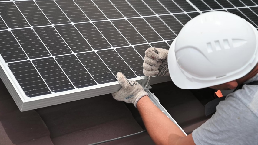 Man worker mounting photovoltaic solar moduls on roof of house. Close up of electrician installing solar panel system outdoors, tightening clamp with hex key. Concept of alternative, renewable energy. Royalty-Free Stock Footage #1086222875