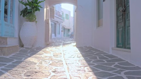Walking in sunlight by cozy greek street in Aegean sea island. Travel to Greece