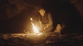 Lockdown Wide Shot Of Man Preparing Vintage Coffee Grinder At Campfire In Cave At Night, Iceland - Powered by Shutterstock - Get 15% off with code: PIKWIZARD15