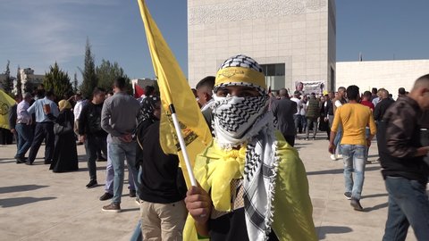 RAMALLAH, WEST BANK – NOVEMBER 11 2021: Young man wearing traditional Palestinian 'keffiyeh' (head dress) stands in front of Yasser Arafat mausoleum in Ramallah (during his death anniversary).