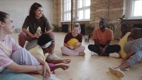Group of young multiethnic dancers in sportswear sitting on floor in studio and chatting while resting after training - Powered by Shutterstock - Get 15% off with code: PIKWIZARD15
